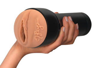 En hand håller i Feel Reya Sunshine Masturbator, en svart Kiiroo-leksak med en mjuk, köttfärgad öppning som är utformad för en anatomiskt realistisk och njutbar upplevelse.