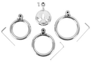 Ett set med en mini-kyskhetsbur med tre silverfärgade metallringar, ett låsbart lock, en skruv och två insexnycklar, avbildat mot en vit bakgrund.