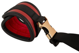 Bondage-set i rött och svart konstläder från hals till handled med guldspännen, bestående av halsband och handbojor som är sammankopplade med remmar.