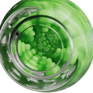 En glasflaska med gröna, människoliknande gelévitaminer bredvid en ljus långärmad tröja med ett enkelt mönster.
