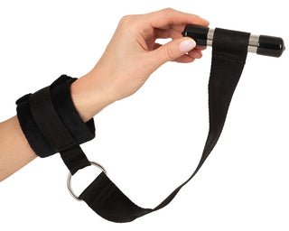 Svart, justerbar fästsats för montering över dörren med vadderade manschetter, nylonremmar och ett cylindriskt handtag.