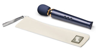 Marinblå Le Wand Petite uppladdningsbar stavvibrator med guldfärgad krage och krämfärgat förvaringsfodral.