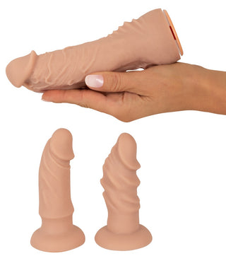 En hand håller Strap-on Set med Vibrator ovanför två mindre modeller som står upprätt på en plan yta, vilket belyser den variation som finns i strap-on-set.