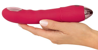 En hand håller i Showers to Orgasm Duschvibrator – en rosa, vattentät och uppladdningsbar silikonvibrator med metallisk accent och 10 intensiva vibrationslägen.