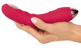 En hand håller i Showers to Orgasm Duschvibrator – en rosa, kurvad design med 10 intensiva vibrationer och metallic-detaljer mot vit bakgrund. Vattentät, uppladdningsbar och perfekt för din bekvämlighet.