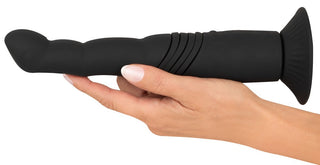 En hand håller G- & P-Spot Thrusting Vibrator, tillverkad av kroppsvänlig silikon med en böjd spets och ribbad bassektion, perfekt för prostatabehandling.