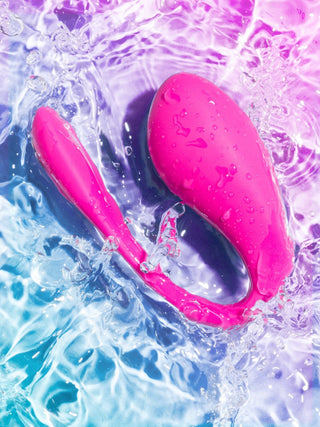 Den rosa vattentäta vibratorn, inspirerad av WeVibe Jive 2, är elegant nedsänkt i virvlande vatten upplyst av blått och rosa ljus.