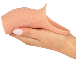 En hand håller försiktigt en Penis Sleeve Öppen Realistixxx, som visar upp dess strukturerade, kötttonade design och öppning.