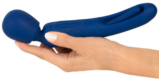 En hand håller 2in1 Wand med Flicking Tongue, med en blå design med dubbla ändar med ett rundat vibrerande huvud på ena sidan och en strukturerad, böjd silikonsektion på den andra.