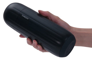 En person håller i en svart, cylindrisk Svakom Sam Neo 2 Pro med en räfflad textur, troligen en elektronisk pryl eller onanist. För interaktiva funktioner, anslut den till SVAKOM-appen mot en vanlig vit bakgrund.