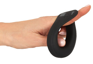 En hand håller Vibrerande Ballring Rebel, en svart silikonring formad för att loopas runt pekfingret - perfekt som erektionsstöd eller vibrerande ballring.