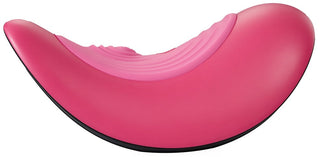 Vibepad RIDE ON är en ljusrosa, böjd, modern loungefåtölj med en slät skulpterad yta och svart bas - perfekt för elegant avkoppling eller handsfree-stimulatorkomfort.