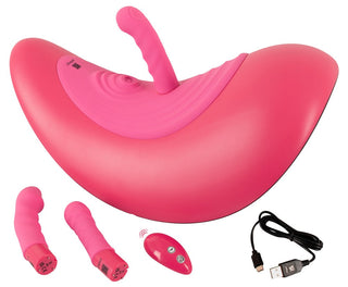 Vibepad RIDE ON: Rosa, böjd leksak för vuxna med klitorisstimulansfästen, fjärrkontroll och USB-laddningskabel mot en vit bakgrund.