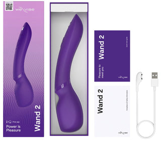 Bilden har en lila We-Vibe Wand 2, tillsammans med en laddningskabel och manualer. Förpackningen hävdar djärvt "Krakt är nöje." Denna massagestav innehåller Smart Silence-teknik för en smidig upplevelse.