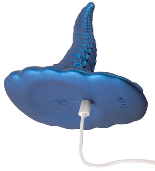 Tentacle Pad Sit On Vibrator är en blå, tentakelformad vibrator med en sugbas och en laddningskabel ansluten till botten.