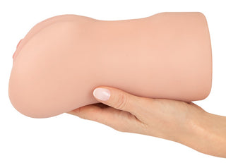 En hand håller Realistixxx RealMasturbator Lösvagina, tillverkad i Natureskin-material med realistisk design och kött-tonad, kurvad form.