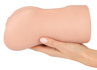 En hand håller Realistixxx RealMasturbator Lösvagina, tillverkad i Natureskin-material med realistisk design och kött-tonad, kurvad form.