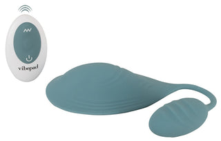 Sittvibrator Vibepad Mini i blå silikon med matchande fjärrkontroll, båda utformade för handsfree-användning, på vit bakgrund.
