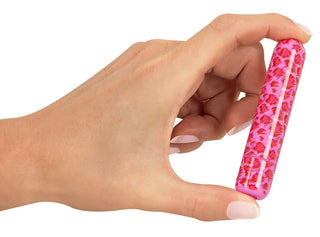 En hand håller LEO Mini Vibrator, en kompakt enhet i rosa prydd med ett djärvt rött blommönster.