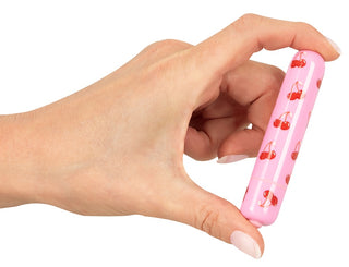 En hand håller CHERRY Mini Vibrator, en rosa, kapselformad enhet med rundade kanter, med ett körsbärsmönster och 10 vibrationslägen.