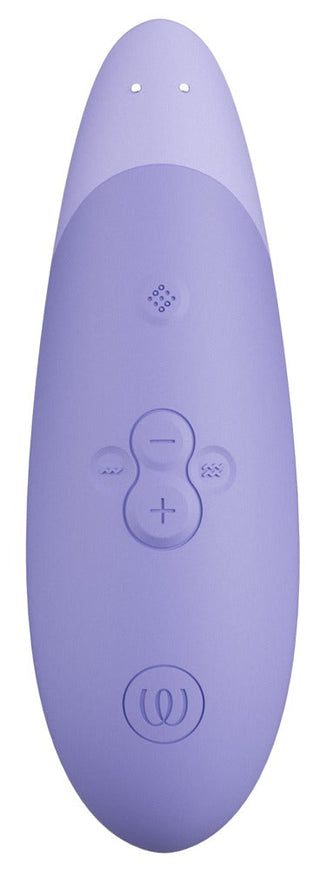 Womanizer Enhance Luftvibrator är en lila, oval elektronisk enhet med flera små vertikala kontrollknappar med plus- och minussymboler. Den innehåller We-Vibes Pleasure Air Technology och har två cirkulära hål i toppen.