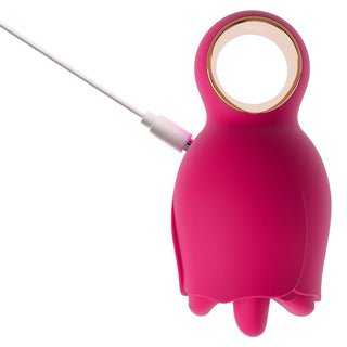 Uggleformad oral vibrator i rosa silikon med rund öppning upptill och vit USB-laddningskabel.