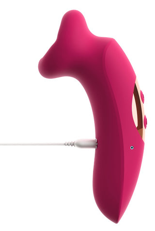 Sugvibrator i rosa silikon med ergonomisk form och kontrollknappar, visas laddas via kabel på vit bakgrund.