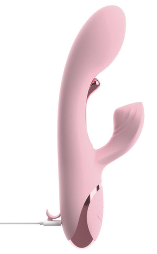 En rosa kaninvibrator i silikon med böjt skaft och yttre stimulator, visas inkopplad för laddning.