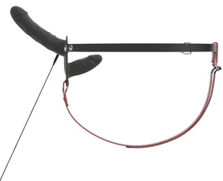 Svart justerbar sele med fastsatt dildo, sett från sidan; tillverkad av syntetmaterial, avsedd för användning som strap-on.