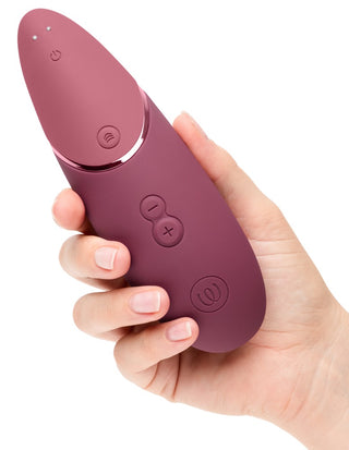 Rödbrun, oval Womanizer NEXT Sensual Collection-stimulator med flera knappar och slät yta.