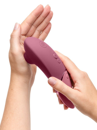 Rosa Womanizer NEXT Sensual Collection-stimulator med slät silikonfinish och knappkontroller, visad från sidan.