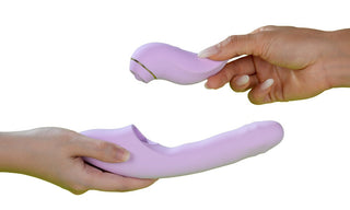 Två händer utbyter ljuslila Svakom DuoGlow 2-i-1-vibratorer, inklusive en kaninvibrator, mot en vit bakgrund.
