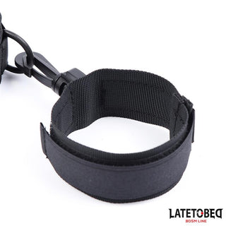 Collar With Wrist Restraints är ett svart justerbart BDSM-tillbehör tillverkat av slitstark nylon med ett metallklämma, som visas på en vit bakgrund. Det passar perfekt ihop med andra handtag eller halsband för mångsidig lek.