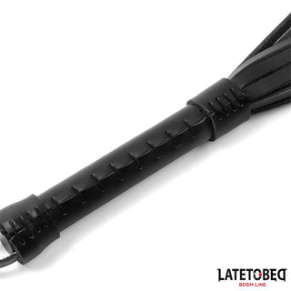 Närbild av Latetobed Läderflogger 50 cm, med ett svart läderhandtag med snörda sömmar. Denna snygga och hållbara sexleksak är perfekt för alla BDSM-samlingar.