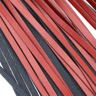 Närbild av röda och svarta läderremsor som läggs parallellt, framhäver strukturen och färgkontrasten, framkallar en lyxig känsla som liknar Mjuk Flogger Piska 40 cm.