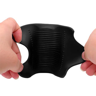 Hands sträcker en flexibel, svart, ribbad Tardenoche Waver Masturbator för män, med ett hål på ena sidan.