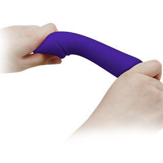 Händerna sträcker ut ett flexibelt, lila föremål som påminner om Mjuk Lila Vibrator Cetus mot en skarp vit bakgrund.