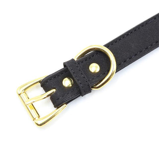 Halsband Med Rosett" är ett förföriskt svart läderbälte med guldspänne och nitar, mot en vit bakgrund.