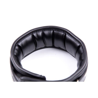 En närbild av en vadderad handledsmanschett i svart läder med sömmar, perfekt ihop med Latetobed Justerbart Halsband för mångsidig användning.