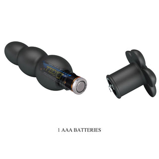 Svart analplugg i silikon med vibrationsfunktion, plats för AAA-batteri och avtagbart lås mot vit bakgrund.