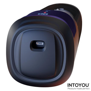 En närbild av INTOYOU Nextor Värmande Masturbator visar upp en högteknologisk enhet med en USB-C-port och en digital LED-display, med "Pleasure made perfect" i hörnet.