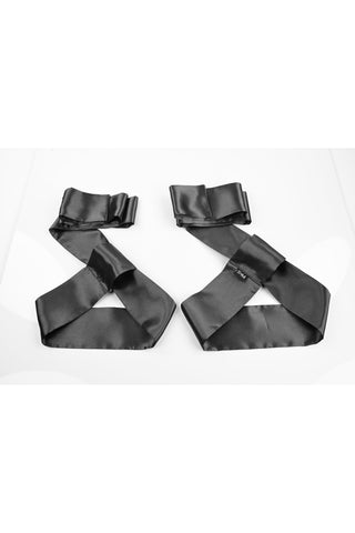 Bondage Kit Svart 5-delar innehåller två svarta satinband med spännen, perfekt för nybörjare eller alla som utforskar BDSM, som visas på en vit yta.