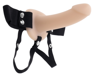 Köttfärgad ihålig strap-on dildo med justerbar svart sele, tillverkad av slätt material, visas på en vit bakgrund.