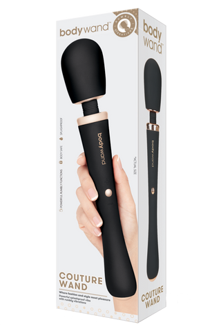 En hand håller i en svart Bodywand Couture Magic Wand-vibrator med silikonskal, som visas tillsammans med sin produktförpackning.