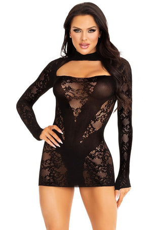 En kvinna poserar självsäkert mot en vit bakgrund i Leg Avenue Mini Dress I Nät, en svart spetsklänning med långa ärmar och utskuren design som utstrålar sensuell elegans med sitt stretchiga nät.