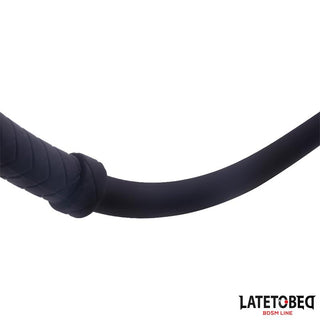 Närbild av Latetobed Silicone Whip 61 cm i svart mot en vit bakgrund, med logotypen LATETOBED BDSM LINE - perfekt för att utforska BDSM och dominanslekar.