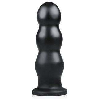Svart, treskiktad silikonskulptur med en rundad topp på en platt bas, designad för intensiv stimulering som XXL Ribbad Buttplug från BUTTR.