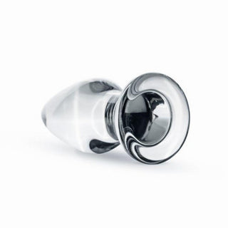 En elegant, böjd transparent glasdörrknopp, som påminner om en Gildo Klar Glasplugg, vilar elegant på en plan yta.