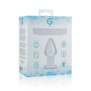 Gildo Glass Buttplug 4,6 cm levereras i en förpackning, tillverkad av temperaturkänsligt borosilikatglas, med produktinformation, diagram och ikoner på en vit och blå geometrisk bakgrund.