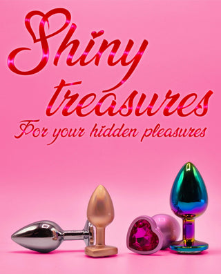 Flera metalliska buttplugs i olika färger och former, inklusive en med hjärtformad kristall, med texten Shiny treasures for your hidden pleasures på mobil